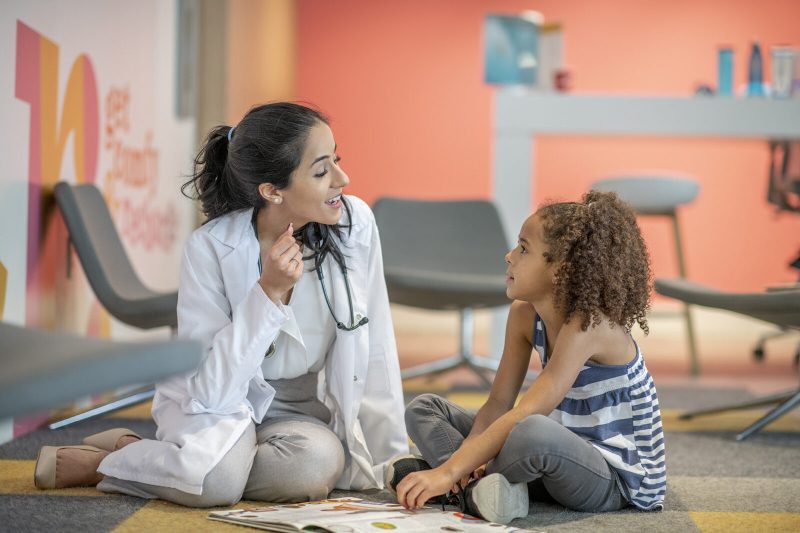 A doctor instructs a young girl how to practice her speech skills.